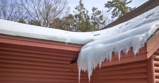 Icicles Hang From Ice Dam On Home Roof With Water Dripping